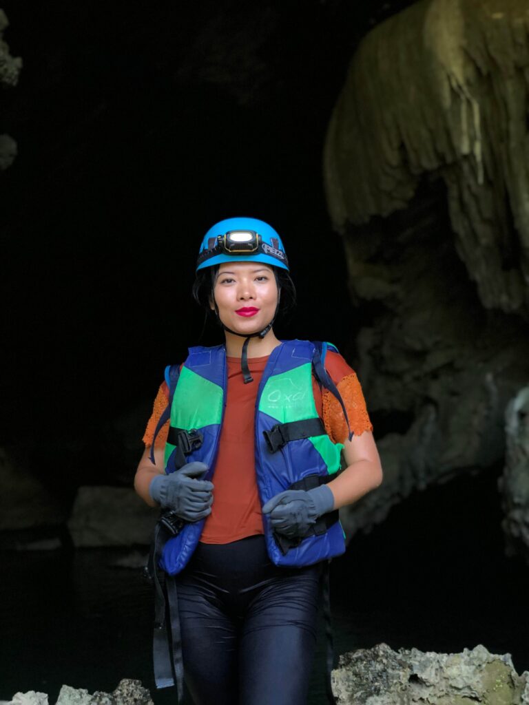 Alex hiking inside a vast cave in Phong Nha, Vietnam, surrounded by dramatic rock formations and soft filtered light.