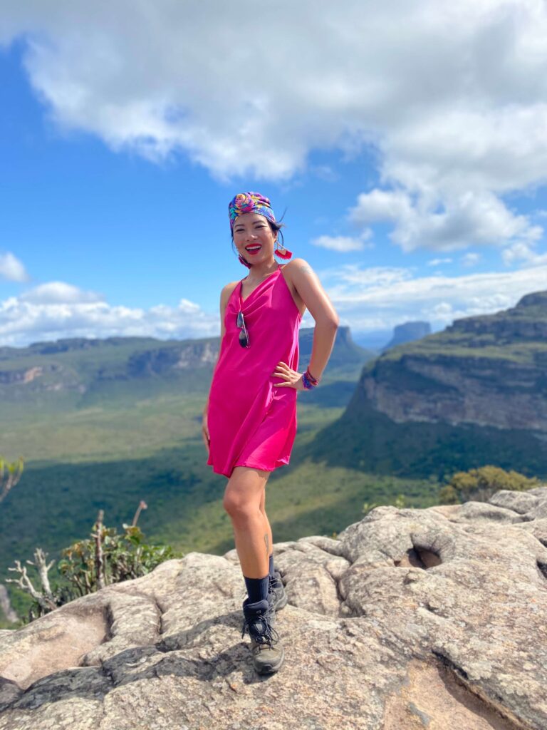 Alex hiking on a mountain top in Brazil, surrounded by lush greenery, dramatic cliffs, and expansive sky views.
