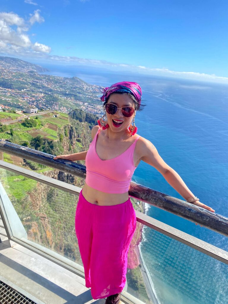 Portrait of a woman standing on the Cabo Girão skywalk, overlooking the cliffs and ocean in Madeira, Portugal